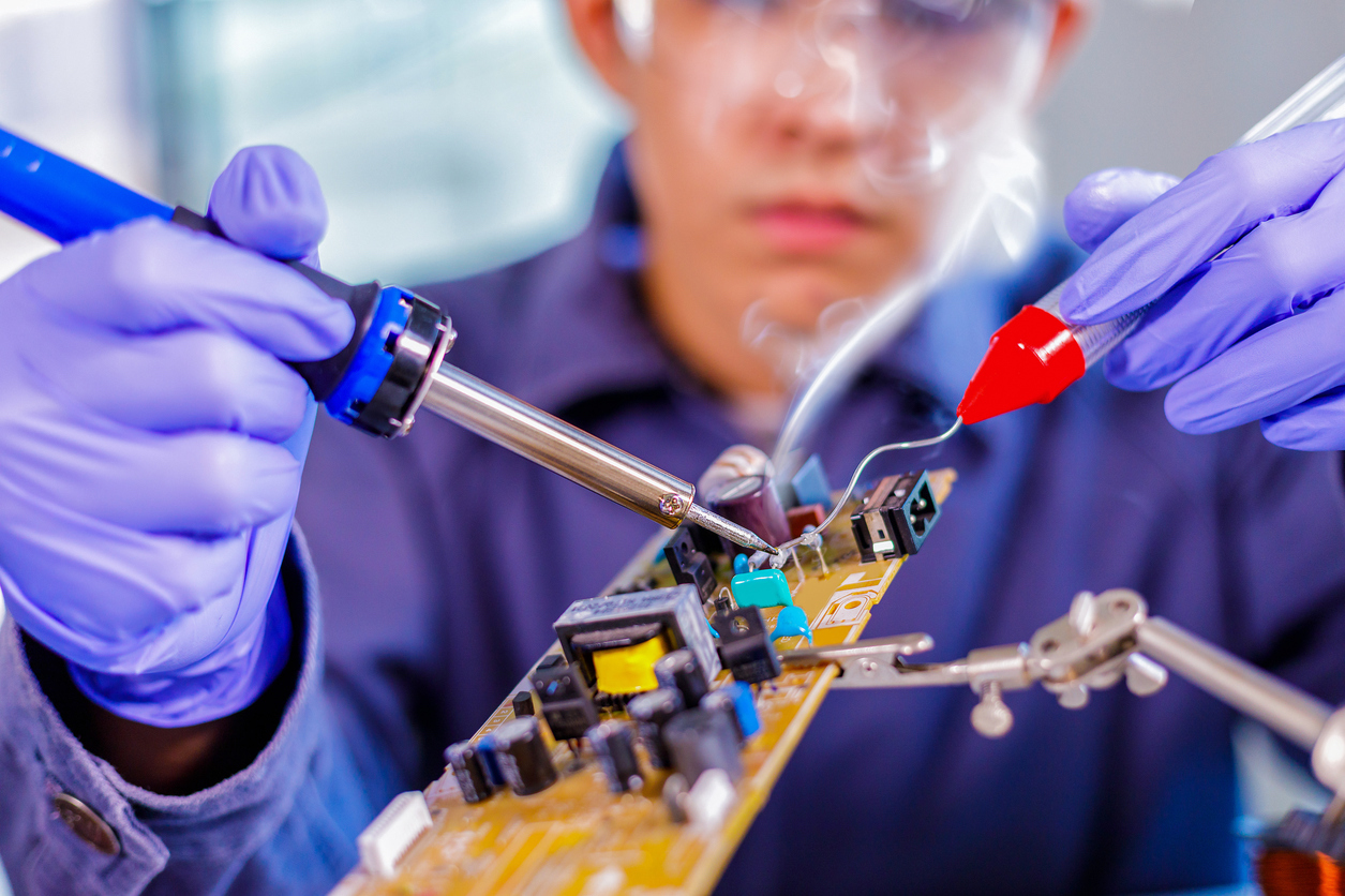 Engineer or technician repair electronic circuit board with soldering iron